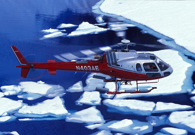 helicopter flying over glacier
